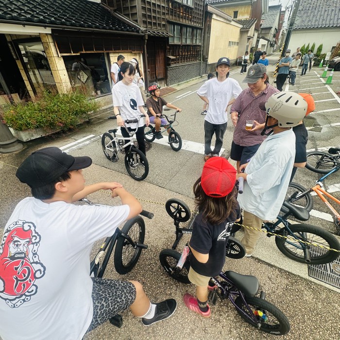 高岡の町並みの中、BMXを囲んで集まる参加ライダーたち