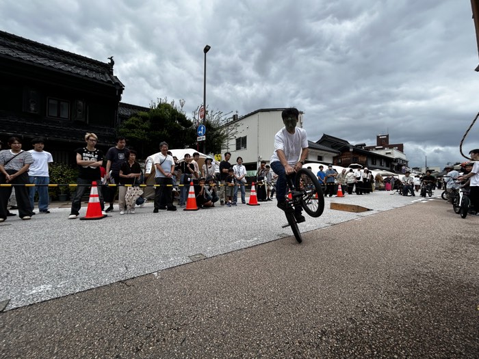 高岡の大仏に扮したアンちゃん選手が市場街でBMXのトリックを披露