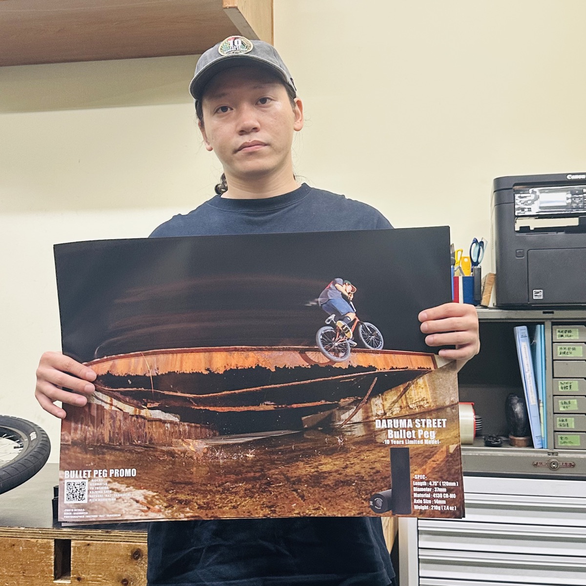 DARUMA STREETのBullet Pegポスターを持つ講師