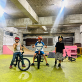 室内のタータスケートパークでBMXと一緒に並ぶ参加者