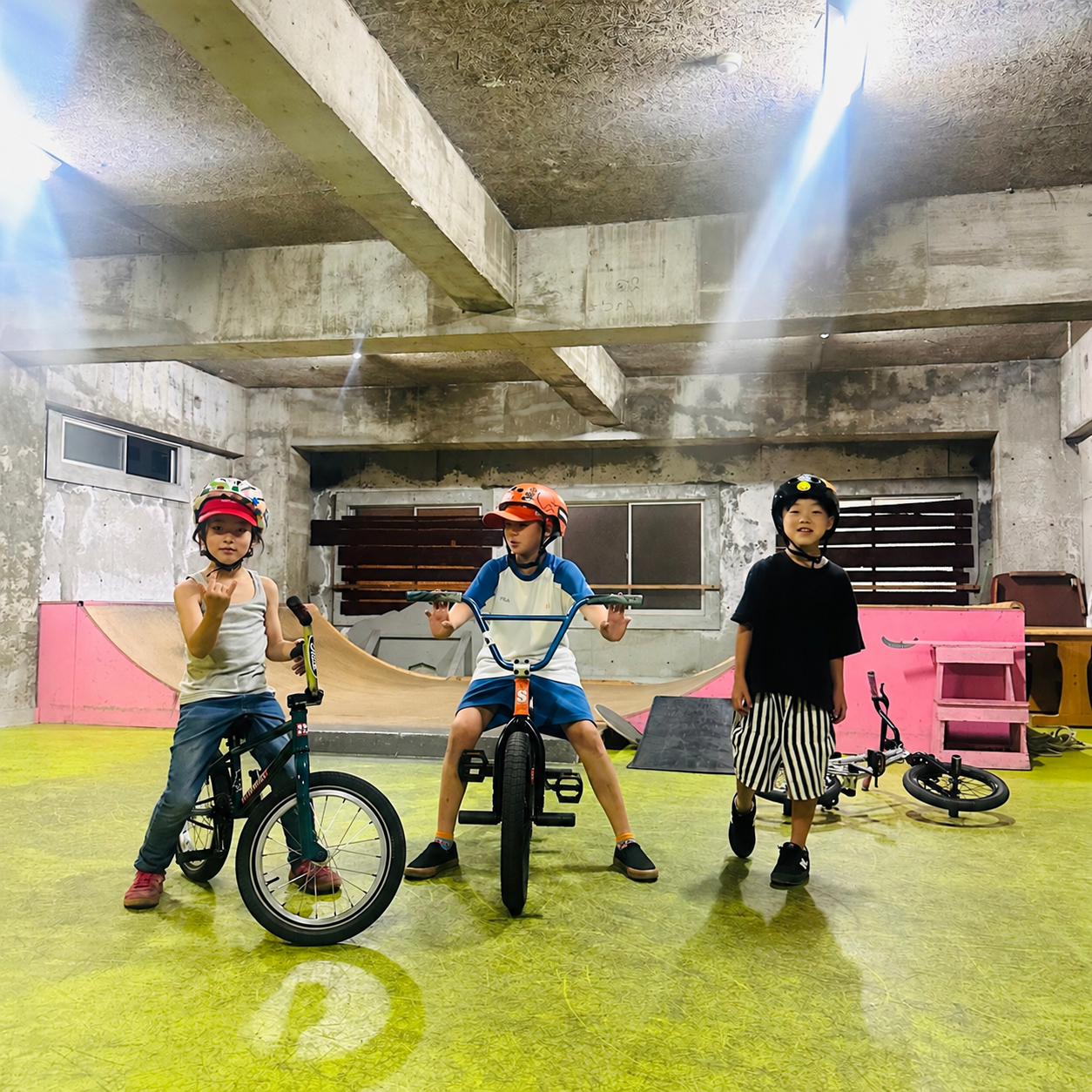 室内のタータスケートパークでBMXと一緒に並ぶ参加者