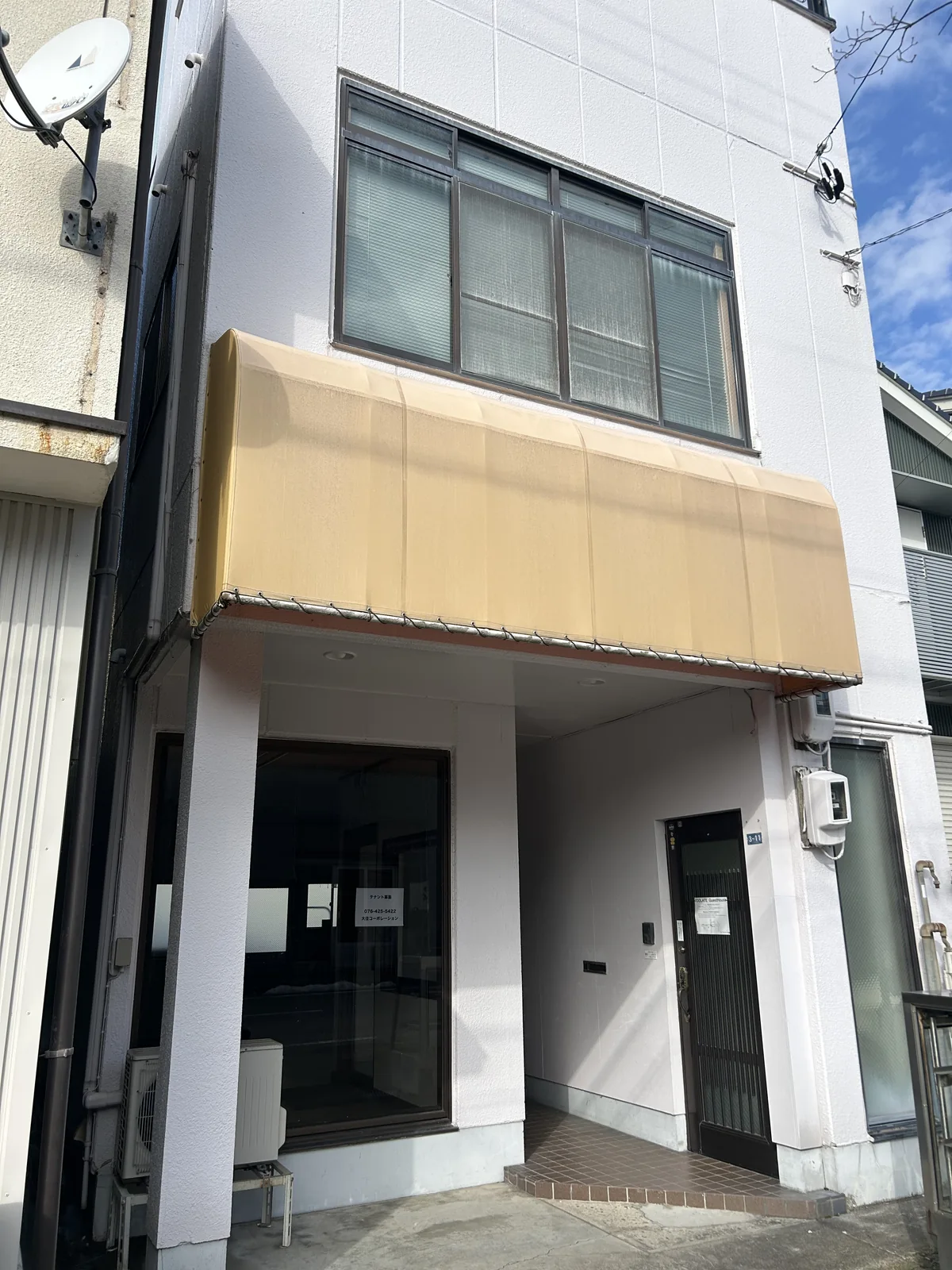 白い外壁と黄色いひさしが目印のゲストハウス外観